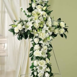 White floral cross on an easel with roses and lilies