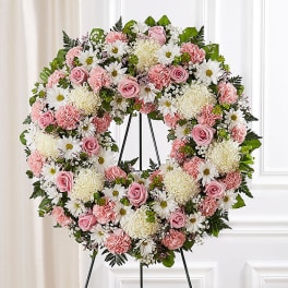 Pink and white floral wreath on a black stand