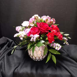Bouquet of red roses and pink flowers in a patterned vase