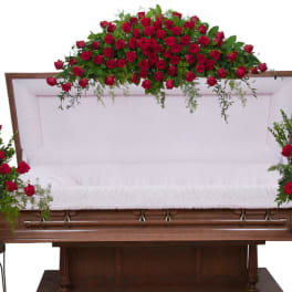 Casket with red rose sprays on top and at both sides