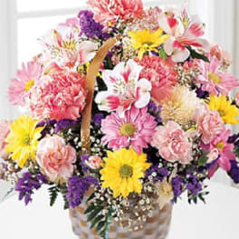 Mixed bouquet of pink, yellow, and purple flowers in a basket