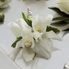 White orchid corsage with green accents and a ribbon-wrapped stem