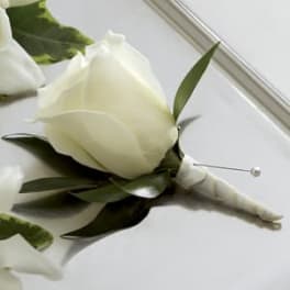 White rose boutonniere with green leaves and a pearl pin