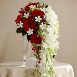 Cascade bouquet of red roses and white orchids in a clear vase