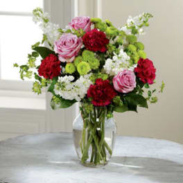 Bouquet of pink roses, red carnations, and white flowers in a glass vase
