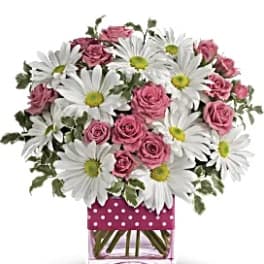 Pink roses and white daisies in a square glass vase with a polka-dot wrap