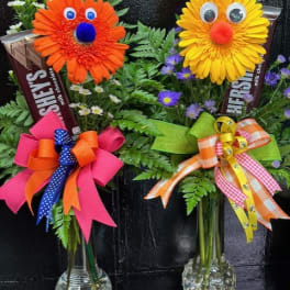 Two novelty flower arrangements with smiling faces in glass vases
