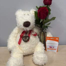 White teddy bear beside two red roses in a glass vase and a Dunkin' gift card