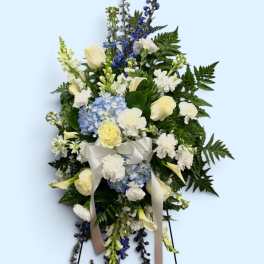 Standing floral spray with white roses, blue hydrangea, and ribbon
