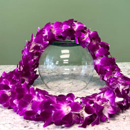 Purple orchid lei draped around a clear glass bowl