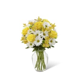 Yellow roses and white daisies in a clear glass vase