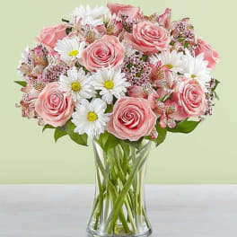 Pink roses and white daisies arranged in a clear glass vase