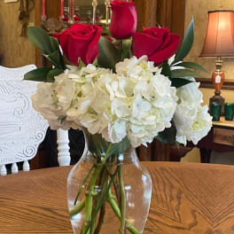 Red roses and white hydrangeas in a clear glass vase