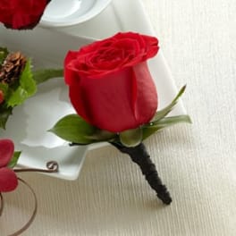 Red rose boutonniere with green leaves on a white tray