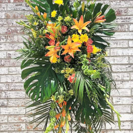Tall tropical floral spray with orange lilies and yellow blooms on a stand