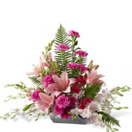 Pink lilies and carnations arranged in a low rectangular container