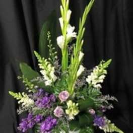 Tall floral arrangement with white and purple blooms in a white vase