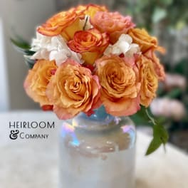 Orange and pink rose bouquet in a glass vase