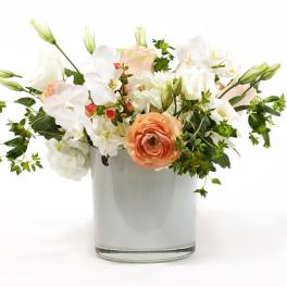 Mixed white and peach flowers arranged in a clear glass vase