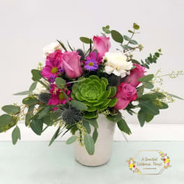 Pink roses and purple flowers in a white vase with a green succulent centerpiece