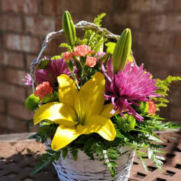 Basket arrangement with yellow lily and pink flowers