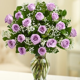 Lavender roses arranged in a clear glass vase with baby's breath