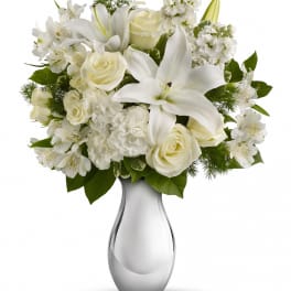 White lilies and roses arranged in a clear glass vase