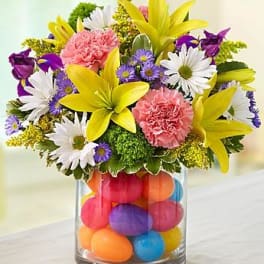 Colorful bouquet in a glass vase filled with bright eggs