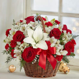 Basket arrangement of red roses and white lilies with a red ribbon