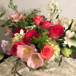 Mixed bouquet of roses, lilies, and alstroemeria in a glass vase