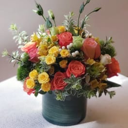 Mixed bouquet of roses and small yellow flowers in a dark vase