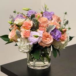 Mixed pastel bouquet of roses and hydrangeas in a clear glass vase