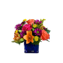 Colorful bouquet in a blue glass vase with roses, lilies, and daisies