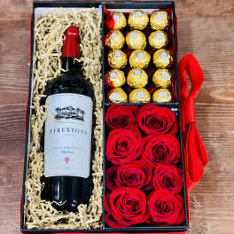 Gift box with a wine bottle, chocolates, and red roses
