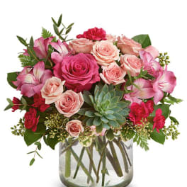 Pink roses and carnations in a glass vase with a succulent accent