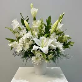 White lilies and chrysanthemums arranged in a white vase