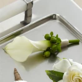 White calla lily boutonniere with green berries on a tray