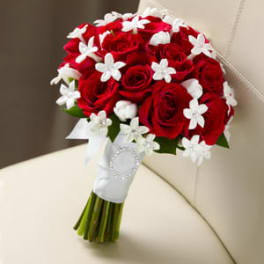 Bouquet of red roses with white star-shaped accents and a white ribbon wrap