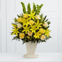 Yellow lilies and pale roses arranged in a cream vase