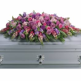 Lavender and pink floral casket spray on a gray casket