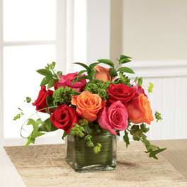 Bouquet of red, pink, and orange roses in a glass vase