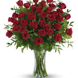 Tall bouquet of long-stemmed red roses in a clear glass vase
