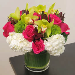 Pink roses and green orchids in a glass vase with white hydrangeas