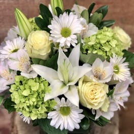 Bouquet of white lilies, pale yellow roses, and daisies with green hydrangea