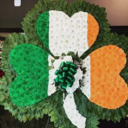 Large floral tribute in green, white, and orange with a bow