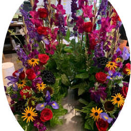 Tall mixed floral arrangement with red roses and purple blooms
