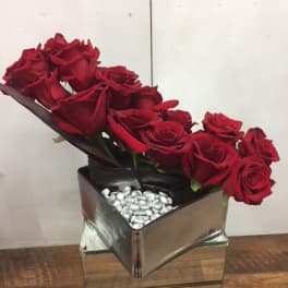 Red roses arranged in a square mirrored vase with silver stones