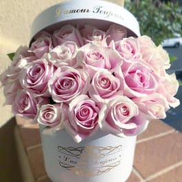 Round white hat box filled with tightly packed light pink roses