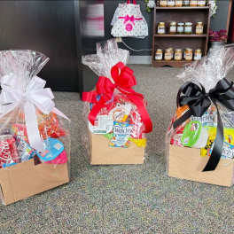 Three wrapped gift baskets filled with snacks and soda