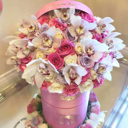 Pink and white roses with white orchids in a pink hatbox